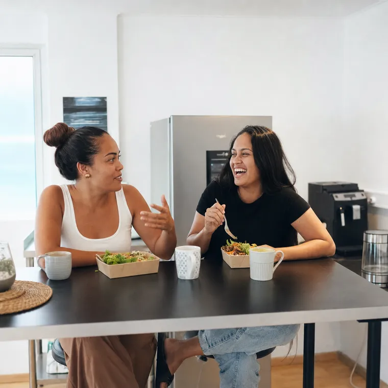 Deux amies déjeunent et rient ensemble à la table haute de la cafétéria